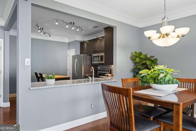kitchen with stainless steel appliances, a chandelier, a sink, ornamental molding, and dark wood-style floors