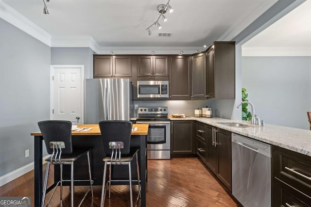 kitchen with appliances with stainless steel finishes, a sink, dark wood-type flooring, dark brown cabinetry, and crown molding