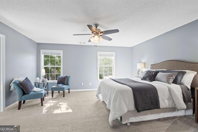 carpeted bedroom featuring multiple windows, baseboards, a ceiling fan, and a textured ceiling