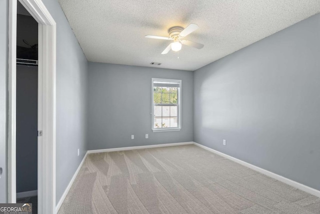 empty room featuring ceiling fan, a textured ceiling, carpet floors, and baseboards
