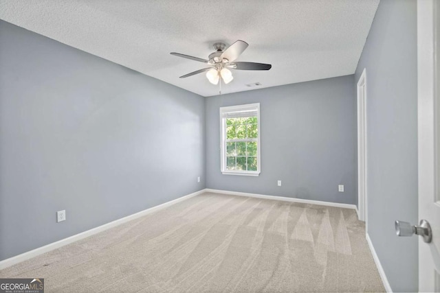 spare room featuring a textured ceiling, carpet, ceiling fan, and baseboards