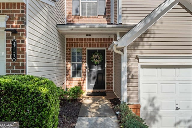 view of exterior entry featuring brick siding and an attached garage