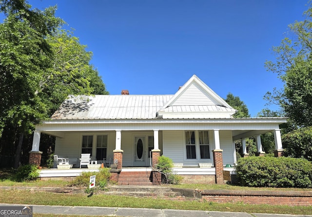 61 Calhoun St, Gibson, GA 30810 - view of front of home featuring covered porch, metal roof, and a chimney