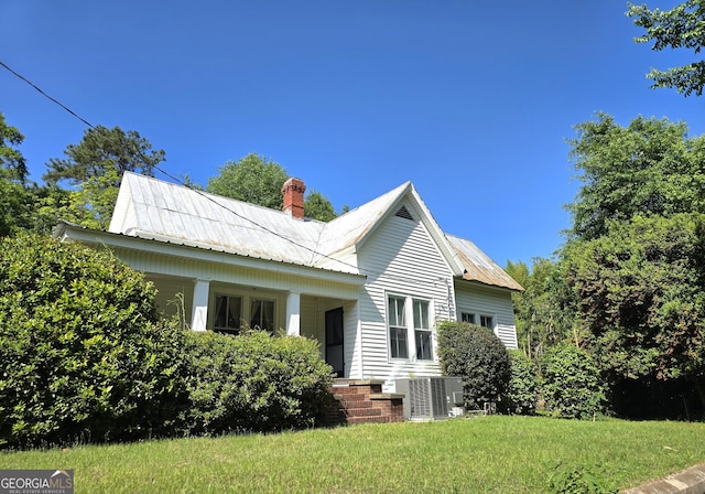 61 Calhoun St, Gibson, GA 30810 - back of property featuring central air condition unit, a chimney, metal roof, and a yard