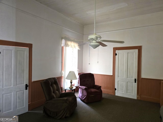 61 Calhoun St, Gibson, GA 30810 - living area featuring a wainscoted wall, ceiling fan, carpet, ornamental molding, and wooden walls