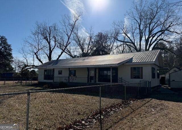 view of front facade with a porch, a fenced front yard, and metal roof