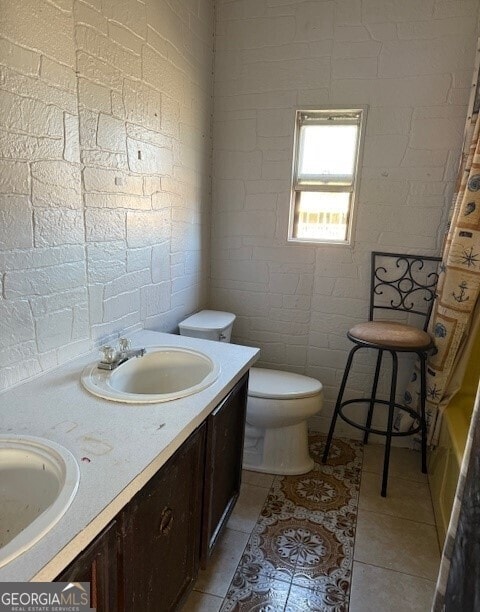 bathroom with toilet, double vanity, and tile patterned flooring