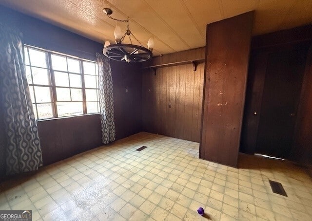 unfurnished dining area featuring tile patterned floors and wood walls