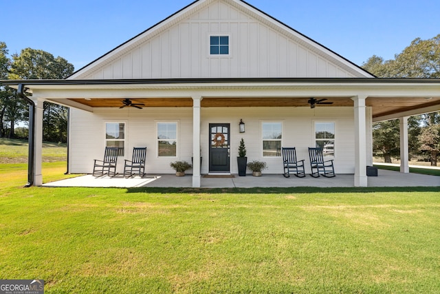 rear view of property featuring ceiling fan, a lawn, and board and batten siding