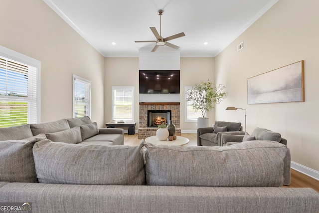 living area with wood finished floors, plenty of natural light, ceiling fan, baseboards, and ornamental molding