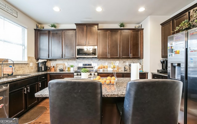 2496 Osceola Rd, Lithonia, GA 30058 - kitchen with appliances with stainless steel finishes, a sink, light stone counters, dark brown cabinets, and a kitchen island