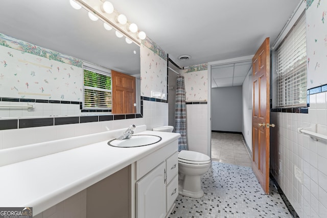 bathroom with tile walls, toilet, vanity, a shower with shower curtain, and wallpapered walls