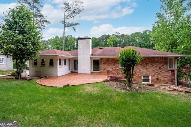 rear view of house with a chimney, a patio area, a lawn, and brick siding