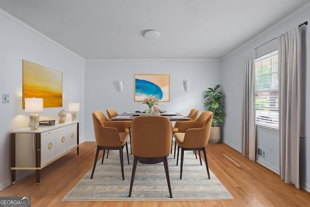 dining space with ornamental molding, light wood-style flooring, and baseboards