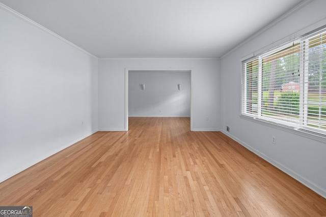 unfurnished room with crown molding, light wood finished floors, and baseboards