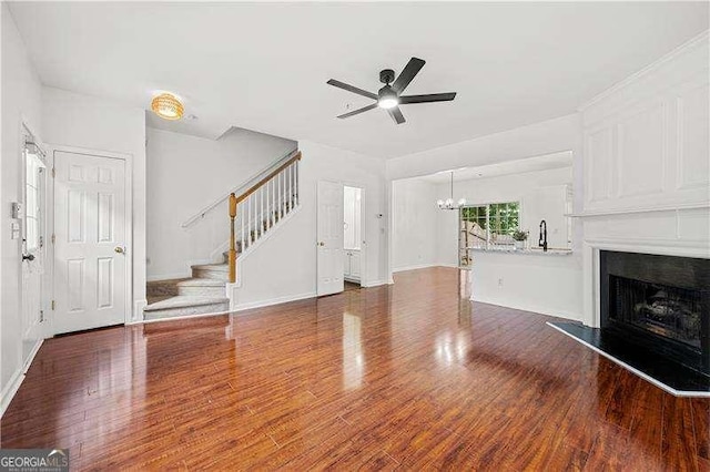 1135 Kilmington Ct, Alpharetta, GA 30009 - unfurnished living room featuring stairs, a fireplace with raised hearth, a chandelier, a ceiling fan, and wood finished floors