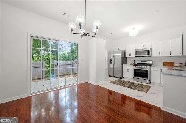 1135 Kilmington Ct, Alpharetta, GA 30009 - kitchen featuring stainless steel appliances, a chandelier, light countertops, white cabinets, and baseboards