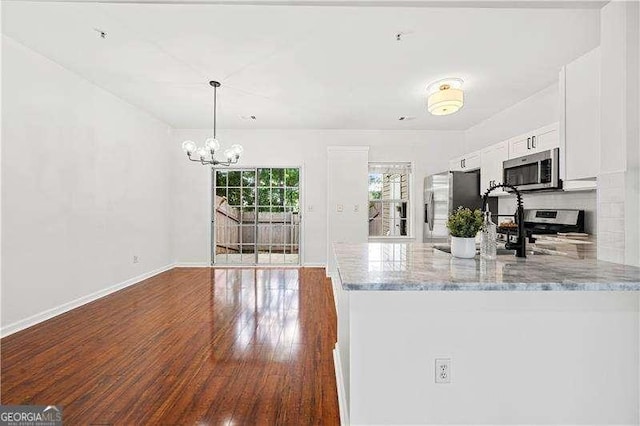 1135 Kilmington Ct, Alpharetta, GA 30009 - kitchen featuring appliances with stainless steel finishes, a chandelier, white cabinets, hardwood / wood-style flooring, and light stone counters