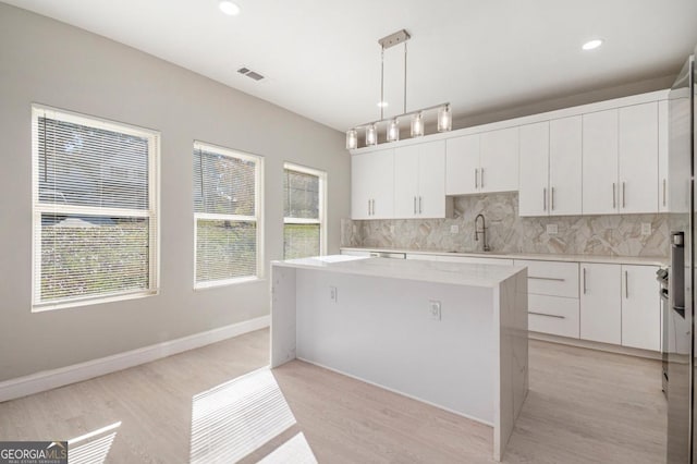7428 Mockingbird Trl, Riverdale, GA 30274 - kitchen featuring decorative backsplash, light wood-style floors, a center island, white cabinets, and recessed lighting