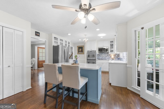 503 Bonnie Dr, Woodstock, GA 30188 - kitchen with stainless steel appliances, light countertops, a kitchen island, white cabinets, and dark wood-type flooring