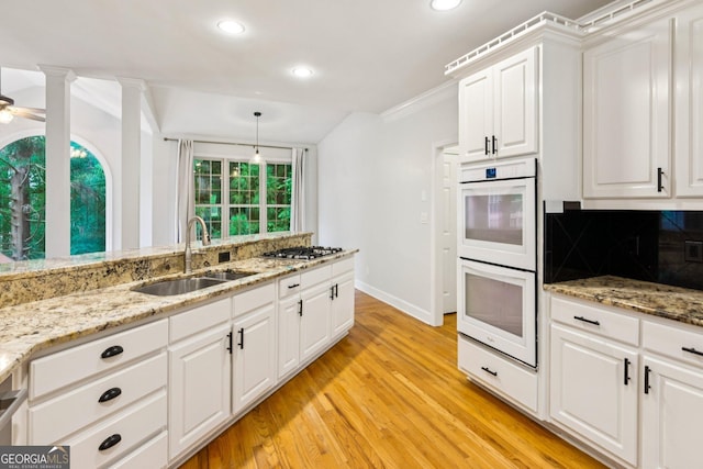 610 Golden Meadows Ln, Suwanee, GA 30024 - kitchen featuring a sink, white double oven, light wood-type flooring, stainless steel gas cooktop, and decorative backsplash