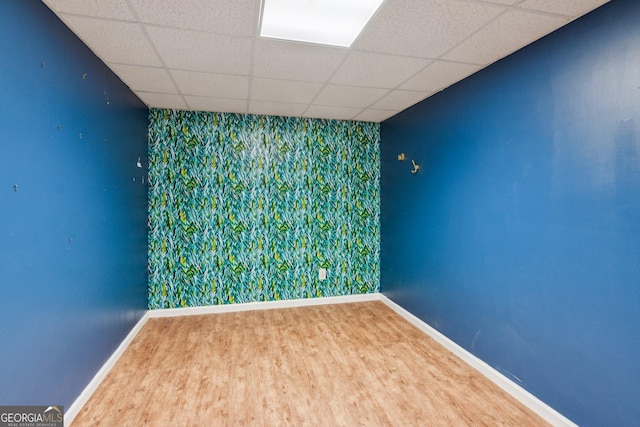 610 Golden Meadows Ln, Suwanee, GA 30024 - unfurnished room with an accent wall, baseboards, a drop ceiling, wallpapered walls, and wood finished floors