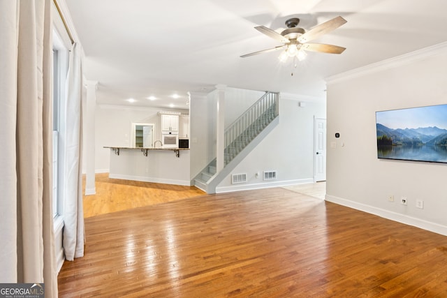 610 Golden Meadows Ln, Suwanee, GA 30024 - unfurnished living room featuring ornamental molding, stairway, light wood-type flooring, a ceiling fan, and baseboards
