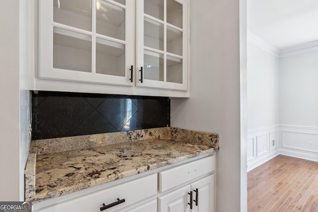 610 Golden Meadows Ln, Suwanee, GA 30024 - kitchen featuring ornamental molding, white cabinets, glass insert cabinets, light stone countertops, and a wainscoted wall
