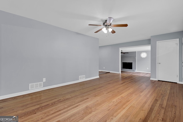 unfurnished living room with a ceiling fan, wood finished floors, baseboards, and a fireplace