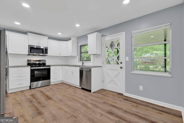 kitchen with appliances with stainless steel finishes, white cabinets, light wood-style flooring, recessed lighting, and baseboards