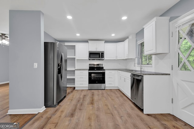 kitchen with stainless steel appliances, a sink, white cabinets, light wood-style flooring, and recessed lighting