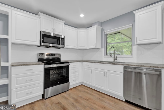kitchen with stainless steel appliances, a sink, tasteful backsplash, white cabinets, and recessed lighting