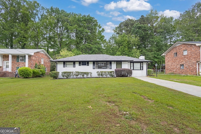 view of front of property featuring a front lawn, brick siding, a chimney, and concrete driveway
