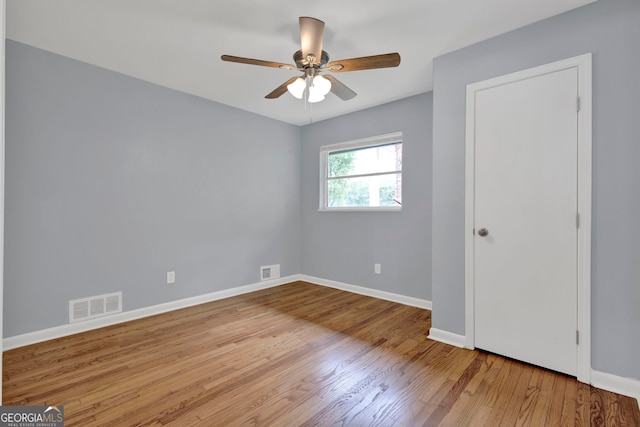 spare room featuring baseboards, wood finished floors, and a ceiling fan