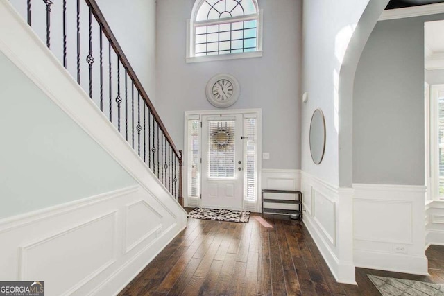 7933 Heathmore Dr, Fairburn, GA 30213 - foyer featuring arched walkways, a decorative wall, dark wood finished floors, a wainscoted wall, and stairway