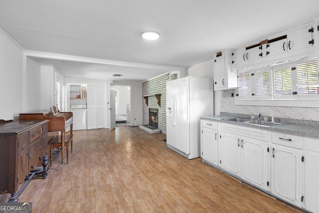 kitchen with white fridge with ice dispenser, a sink, washer / dryer, and white cabinets
