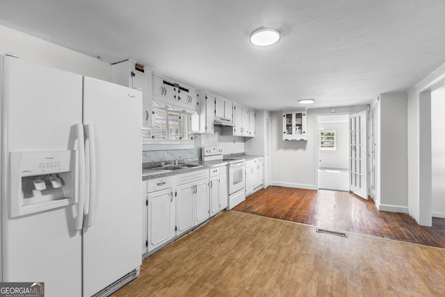 kitchen featuring white appliances, under cabinet range hood, wood finished floors, and healthy amount of natural light