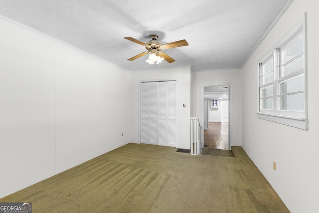 unfurnished bedroom with ornamental molding, carpet flooring, ceiling fan, and a closet
