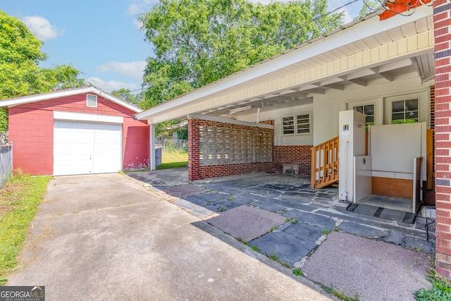 view of patio featuring an outbuilding, a detached garage, driveway, and fence