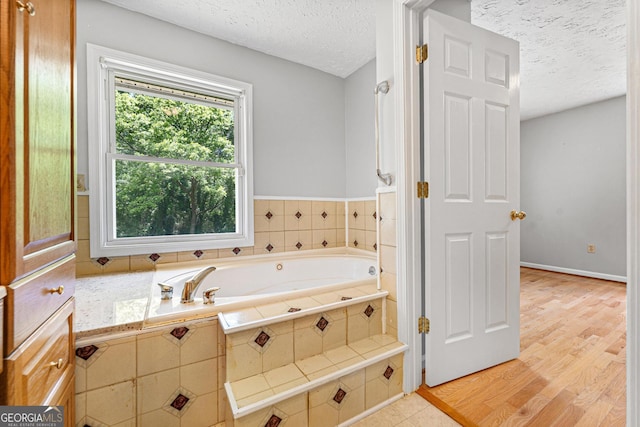 bathroom featuring a textured ceiling, a bath, and wood finished floors