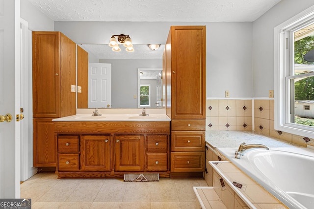 bathroom featuring a textured ceiling, a garden tub, double vanity, and tile patterned floors