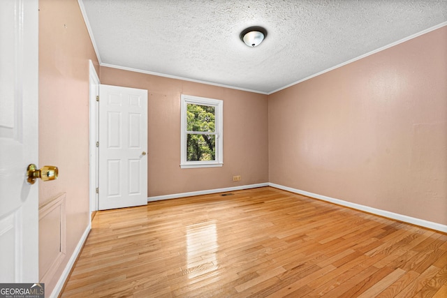 spare room featuring light wood-style floors, crown molding, a textured ceiling, and baseboards