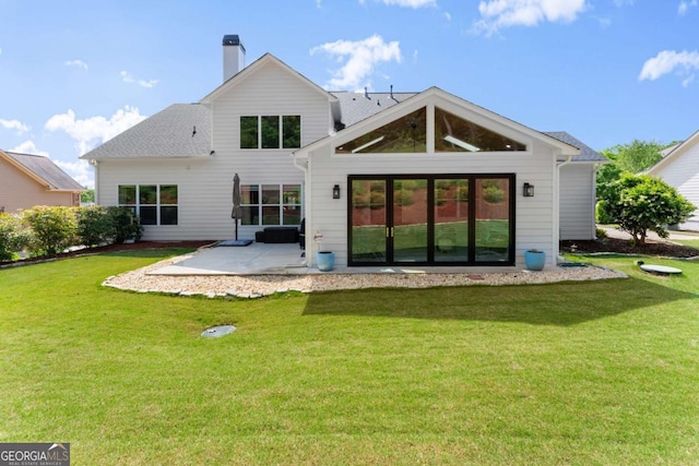 back of property featuring a patio area, a chimney, and a yard