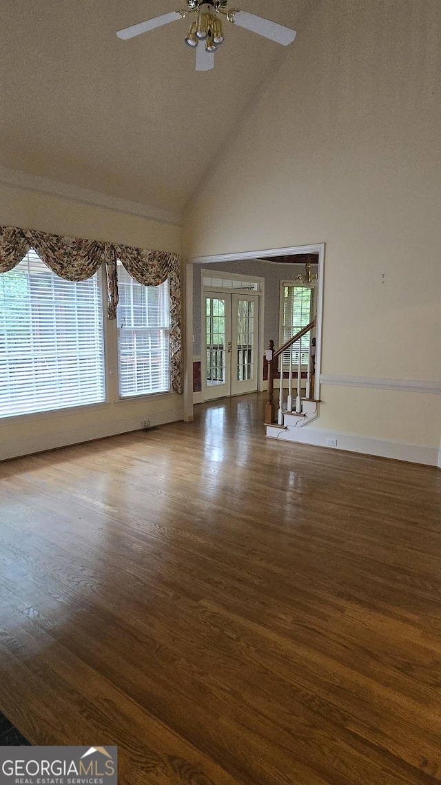 empty room with high vaulted ceiling, wood finished floors, a ceiling fan, healthy amount of natural light, and french doors