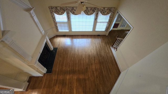unfurnished living room with a ceiling fan, wood finished floors, and a fireplace