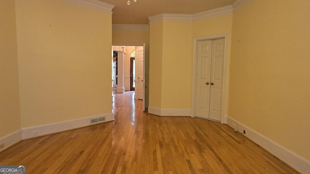 empty room featuring crown molding, wood finished floors, and baseboards
