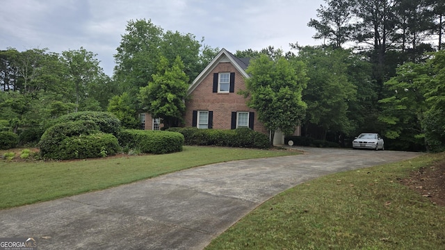 view of front of home featuring brick siding, driveway, and a front lawn
