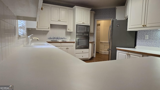 kitchen featuring oven, a sink, freestanding refrigerator, built in microwave, and white cabinets
