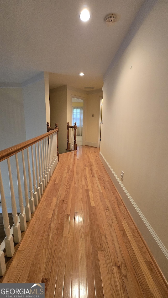 corridor featuring light wood-type flooring, recessed lighting, an upstairs landing, and baseboards