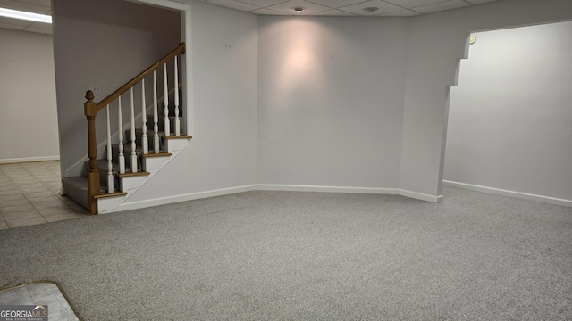 finished below grade area with a drop ceiling, carpet floors, stairway, and baseboards